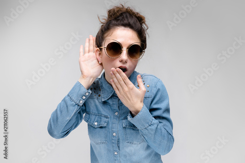 Young brunette girl in black glasses. Cat glasses. The hair is gathered in a bun. The girl eavesdrops. photo