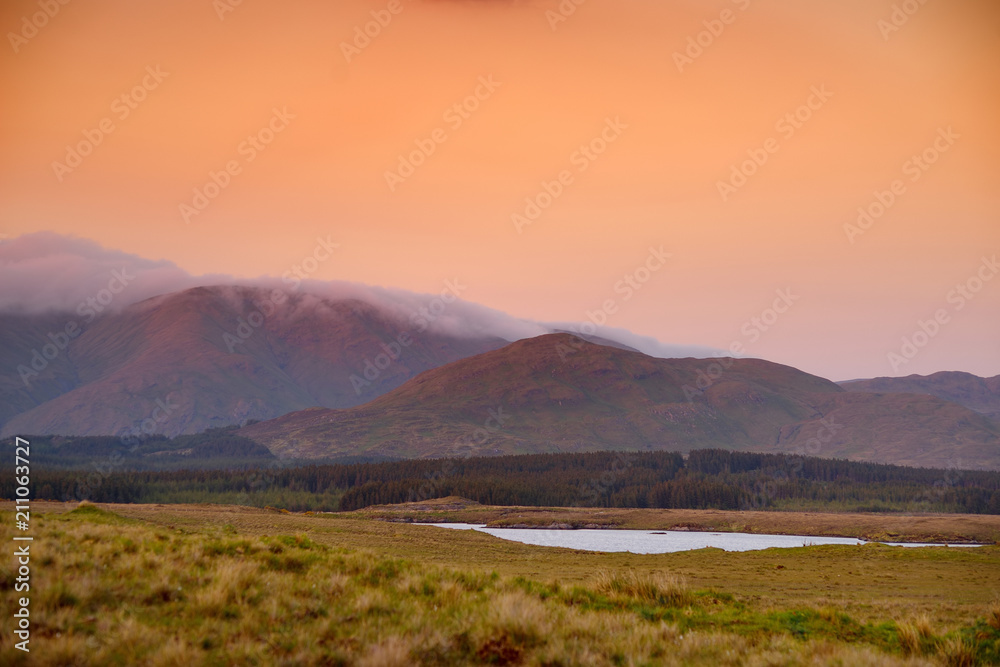 Beautiful sunset view of Connemara. Scenic Irish countryside landscape with magnificent mountains on the horizon, County Galway, Ireland.