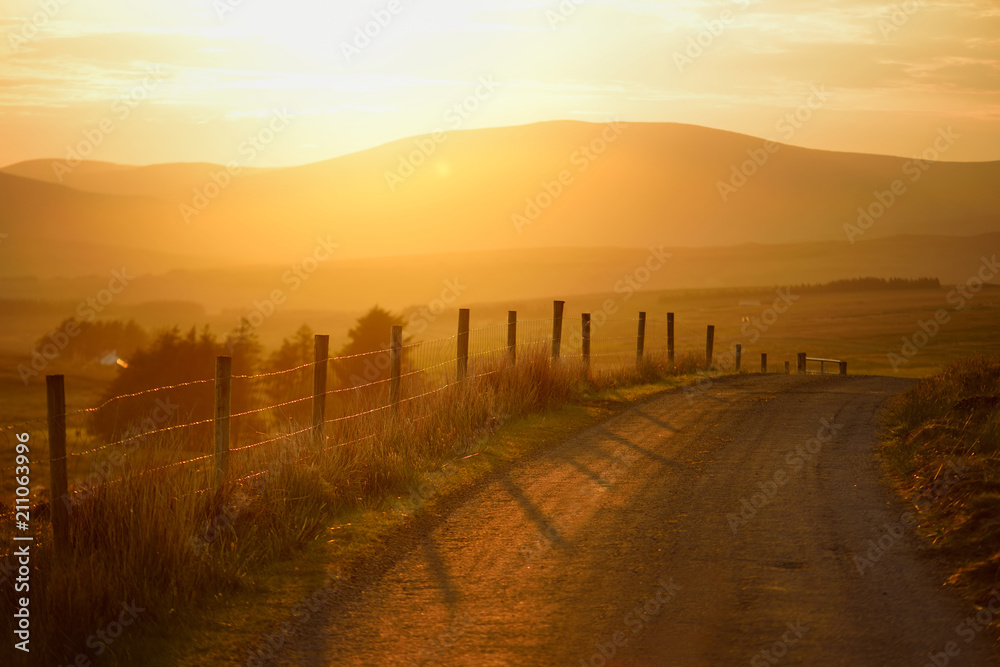 Beautiful sunset in Connemara. Scenic countryside road leading towards magnificent mountains, County Galway, Ireland.