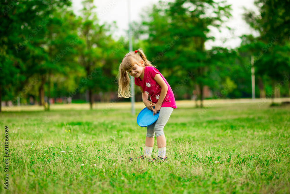 Little girl play with flying disk in motion, playing leisure activity games in summer park Little girl play with flying disk in motion, playing leisure activity games in summer park