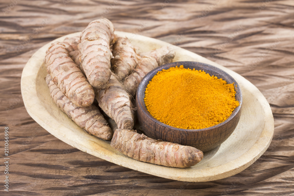 Turmeric powder and fresh turmeric on wooden background. Curcuma longa