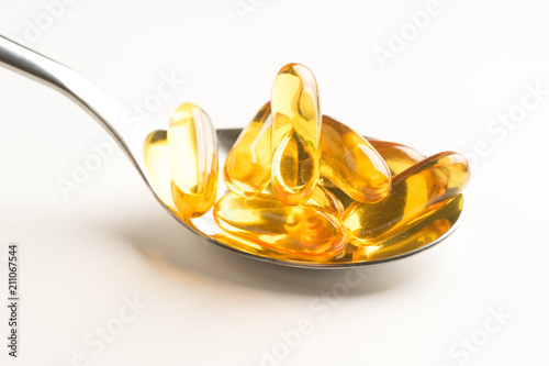 fish oil capsules in a spoon on white