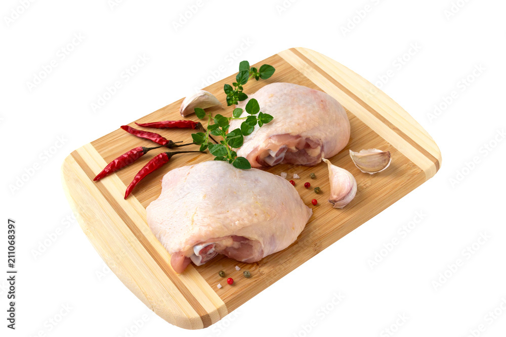 Raw chicken thighs with thyme  on cutting board, on a white background.