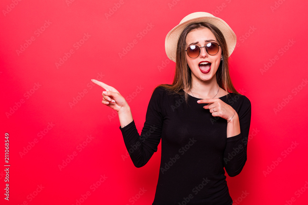 Fototapeta premium Woman showing pointing on red background. Very fresh and energetic beautiful young girl smiling happy presenting on red background.