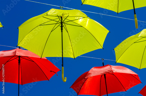 Colourful umbrellas urban street decoration. Hanging colorful umbrellas over blue sky  tourist attraction