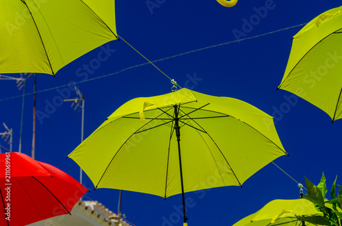 Colourful umbrellas urban street decoration. Hanging colorful umbrellas over blue sky  tourist attraction