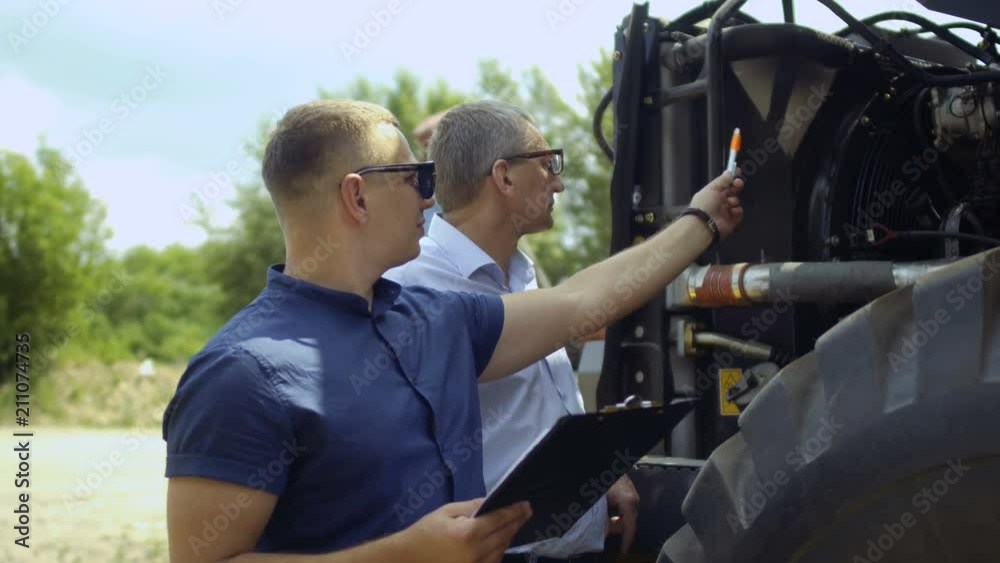 Farmer inspects tractor from outside and talks with seller