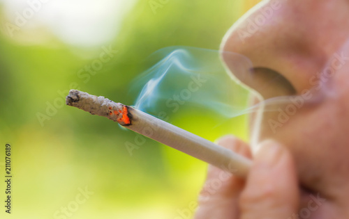 eine Person raucht draußen eine Zigarette