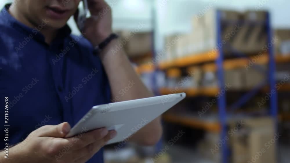 Man hold tablet and talk on phone in storage Man hold tablet and talk on phone in storage