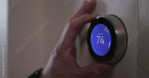 Man Turning Down Temperature of Smart Thermostat Gadget At Home - Close photo