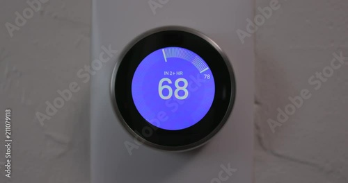 Man Decreasing Temperature of Smart Thermostat Gadget At Home - Medium