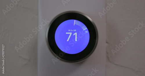 Woman Adjusting Temperature of Smart Thermostat Gadget At Home - Close