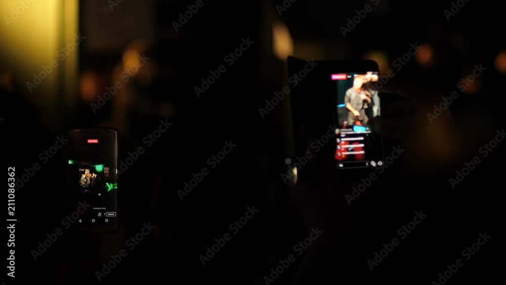 Spectators raise hands shoot mobile phone video of free music concert for social media