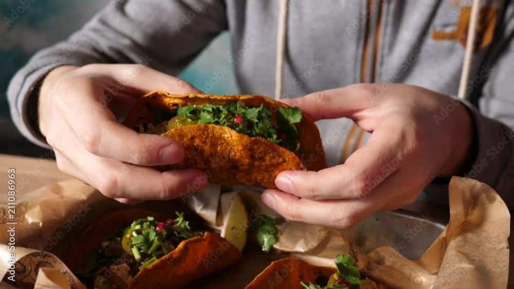 Young man in Mexican cuisine restaurant eating tacos