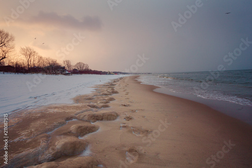 Beach covered by ice with footprints on the sand
