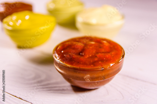 Different sauces in glass bowls on wooden table