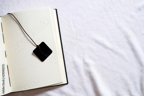 Top view collection of black leather notebook and bookmark with grid paper on white background