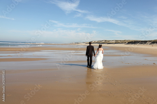 back view Newlyweds sharing a romantic moment at the beach groom and bride walking on sand beach