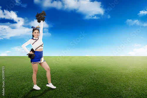 Happy asian cheerleader in action with pom poms