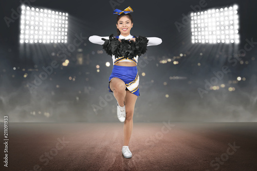 Принти на полотні Young asian cheerleader in action with pom poms
