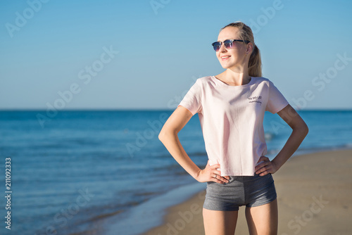 Young attractive woman doing morning exercises on the beach