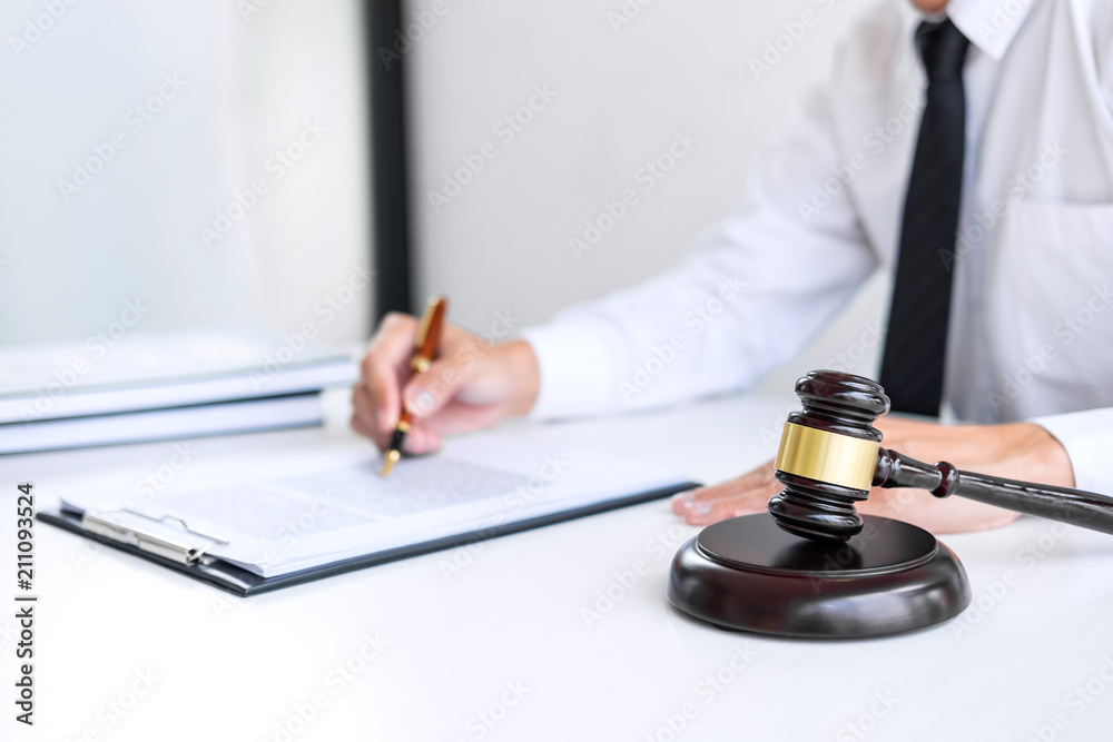 Businessman or lawyer working on a documents, judge gavel with Justice lawyers at law firm in background, Legal law, advice and justice concept Businessman or lawyer working on a documents, judge gavel with Justice lawyers at law firm in background, Legal law, advice and justice concept
