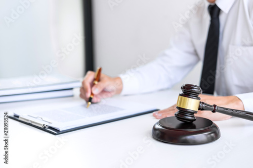 Businessman or lawyer working on a documents, judge gavel with Justice lawyers at law firm in background, Legal law, advice and justice concept