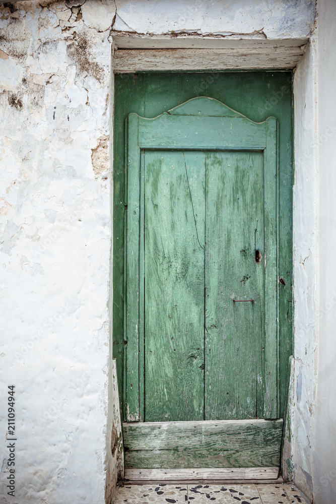 Front door. Old greenish blue wooden door and weathered dirty wall