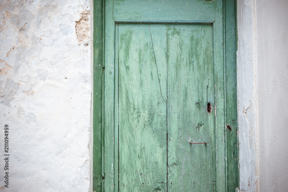 Old greenish blue wooden door and eroded white wall. Front door Old greenish blue wooden door and eroded white wall. Front door