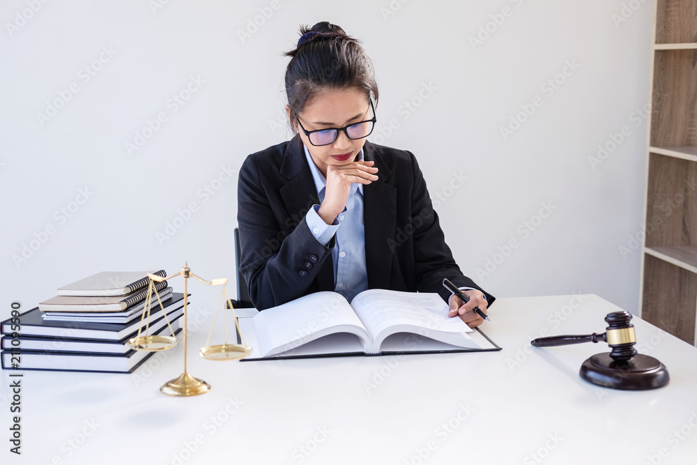 Legal law, advice and justice concept, Professional Female lawyers working on courtroom sitting at the table and signing papers with gavel and Scales of justice Legal law, advice and justice concept, Professional Female lawyers working on courtroom sitting at the table and signing papers with gavel and Scales of justice