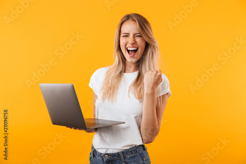 Photography Portrait of an excited young blonde girl holding laptop