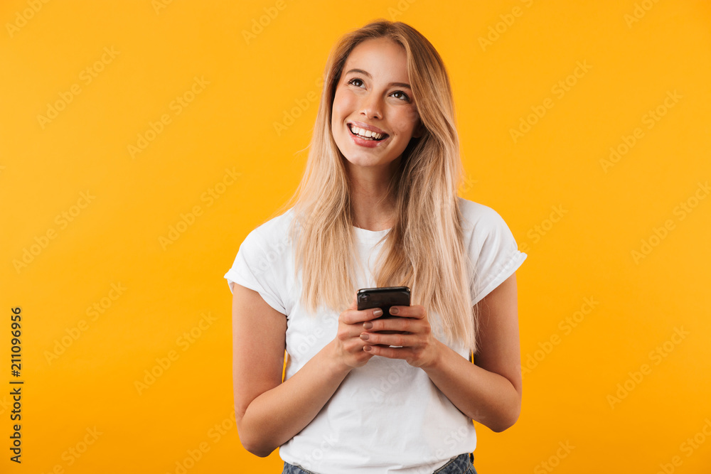 Naklejka premium Portrait of a smiling young blonde girl holding mobile phone
