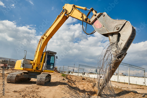 excavator crasher machine crushing pole wit jaws on construction site