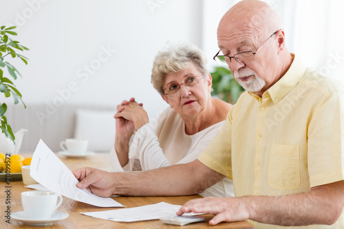 Elderly couple calculating costs of household. Senior people with low pension photo