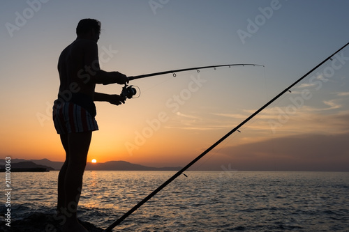 Man fishing with rod in sea at sunset, summer in Greece