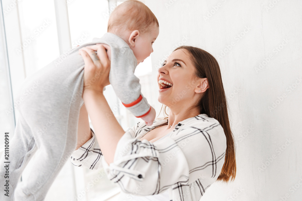 Happy young woman mother holding in hands her little son