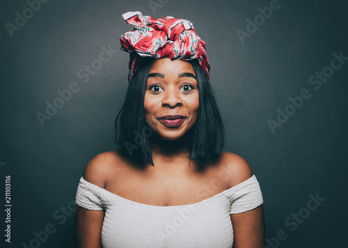 Portrait of excited woman wearing head tie over gray background photo