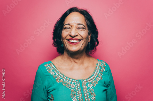 Portrait of smiling senior woman wearing salwar kameez against pink background photo