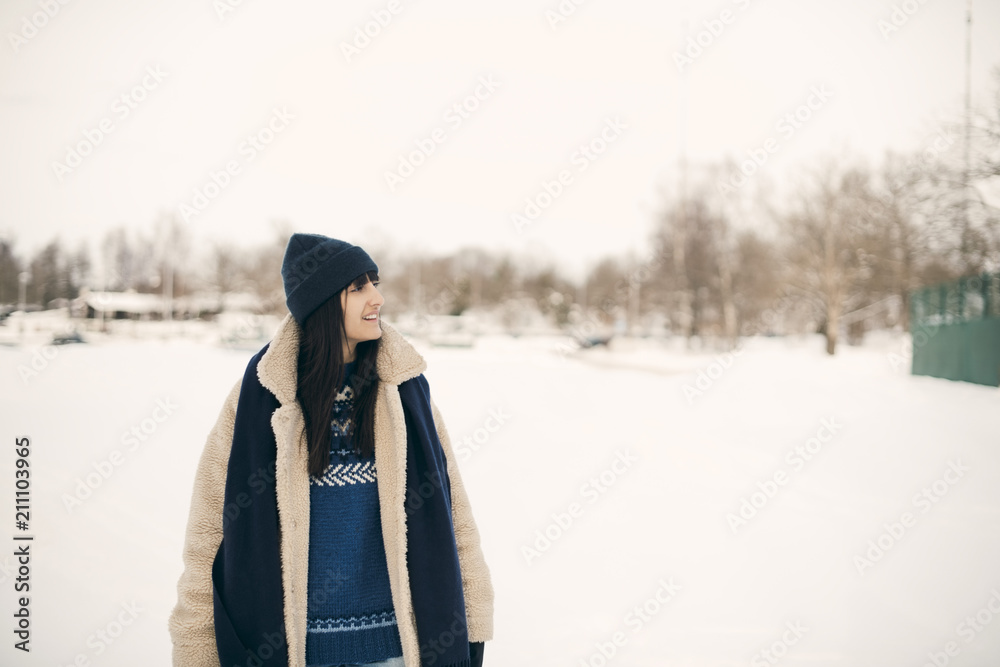Smiling woman looking away while standing on snowy field during winter Smiling woman looking away while standing on snowy field during winter