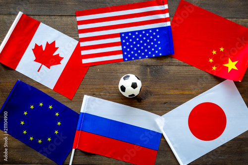 Football championat. American, Canadian, European, Japanese, China, Russian flags and football ball on dark wooden background top view photo