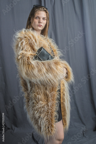 A young girl in a fur coat with a cloak with a handbag and an evening dress glamorous
