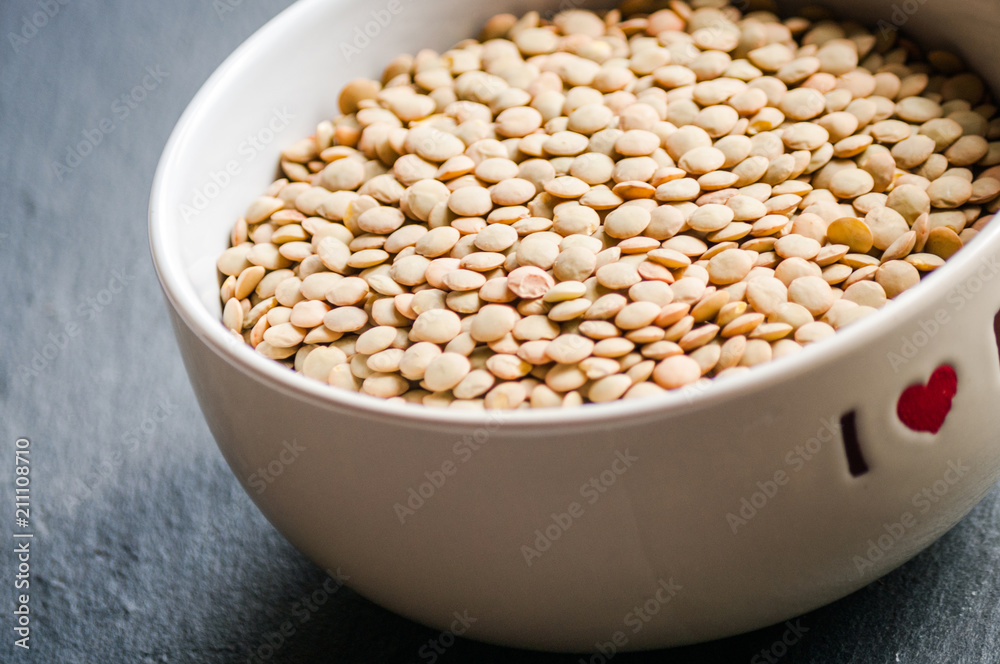 White ceramic bowl of green uncooked lentils isolated on black in perspective White ceramic bowl of green uncooked lentils isolated on black in perspective
