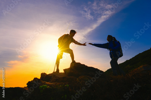 Young asian couple climbing up on the mountain,hiking and team work concept.