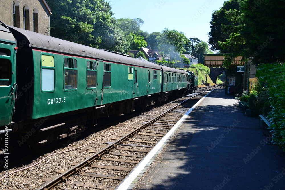 A steam train pulling coaches waiting to depart from a station. A steam train pulling coaches waiting to depart from a station.