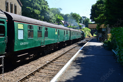A steam train pulling coaches waiting to depart from a station.