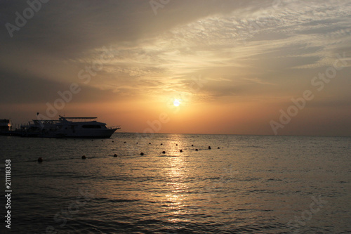 Suset on the sea. Boats on the water. Warm rays of sun light.