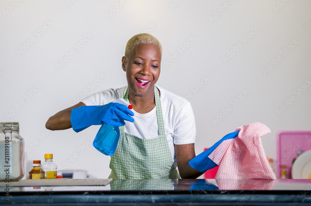 young beautiful and happy African American black woman in washing rubber clothes cleaning home kitchen with cloth smiling cheerful and positive young beautiful and happy African American black woman in washing rubber clothes cleaning home kitchen with cloth smiling cheerful and positive