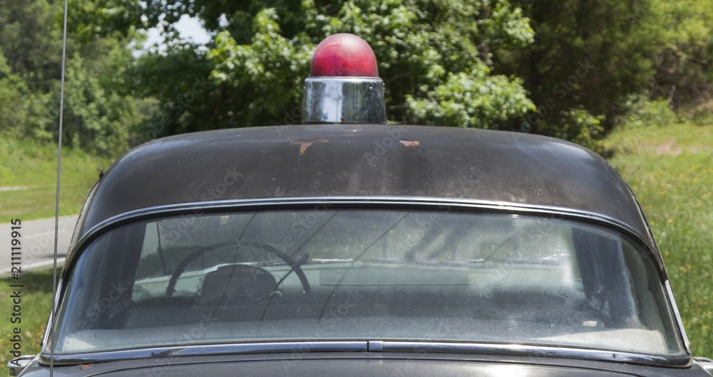 Obraz premium Vintage 1950s Sheriff's patrol car parked on grassy knoll.