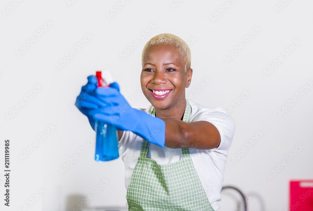 young beautiful and happy black afro american woman using detergent spray bottle as gun smiling playful cleaning and washing home kitchen isolated young beautiful and happy black afro american woman using detergent spray bottle as gun smiling playful cleaning and washing home kitchen isolated