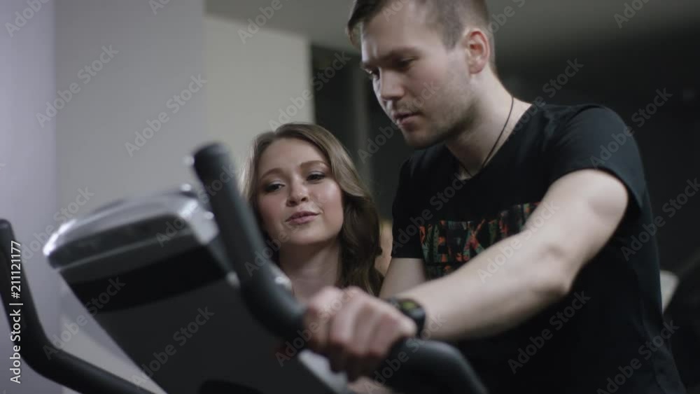 guy pedals on the stationary bike but girl tell him how to switch speeds on this trainer in the new gym guy pedals on the stationary bike but girl tell him how to switch speeds on this trainer in the new gym